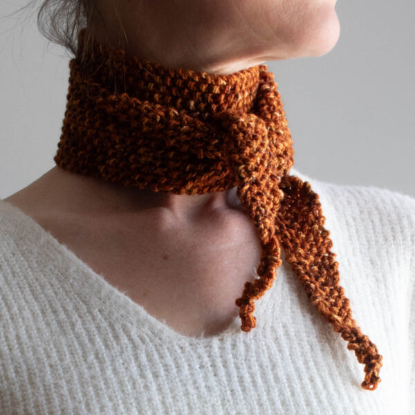 Side view of a cozy seed stitch skinny scarf tied kerchief-style