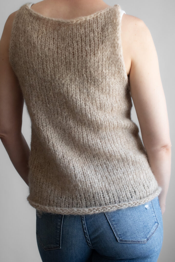 A model wearing a handknitted brushed alpaca tank top in oatmeal, shown from the back angle.