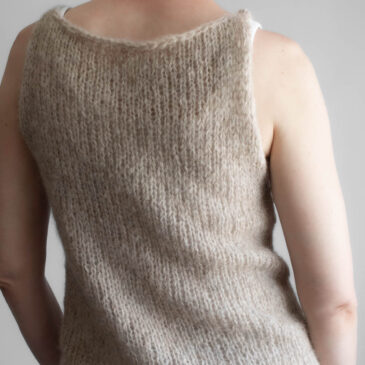 A model wearing a handknitted brushed alpaca tank top in oatmeal, shown from the back angle.